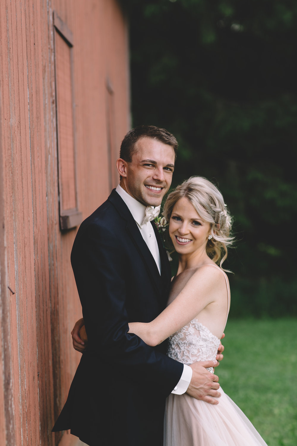 groom and bride in front of barn
