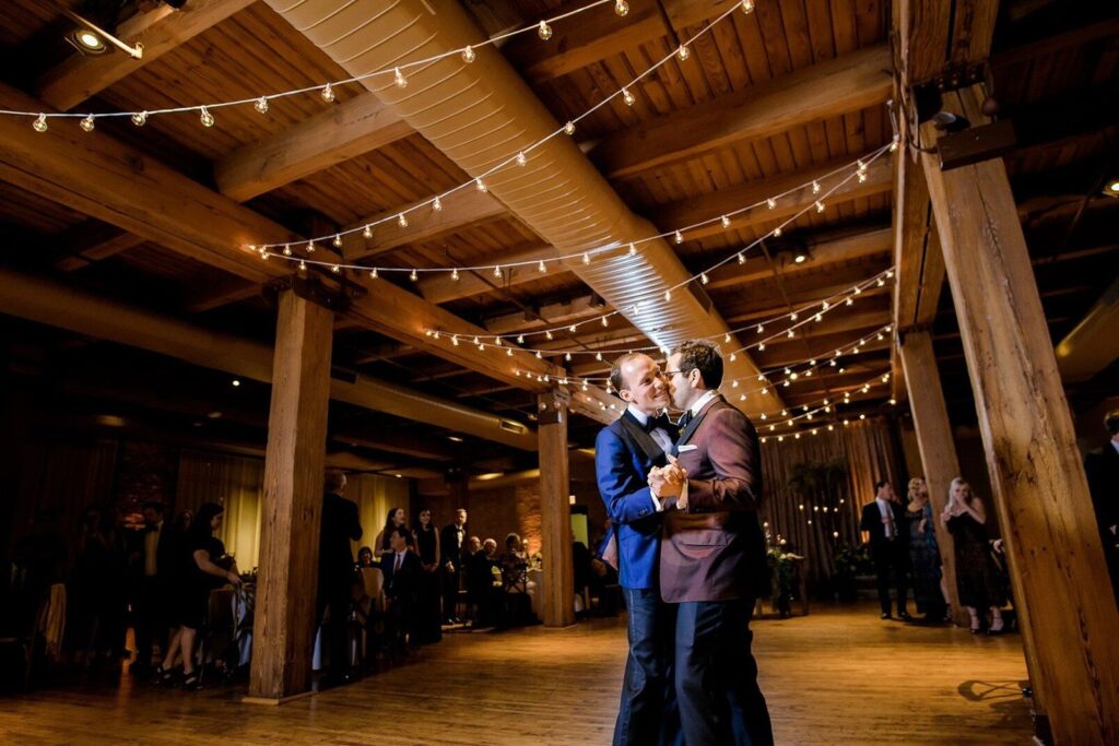 Grooms dancing under bistro lights at wedding reception 