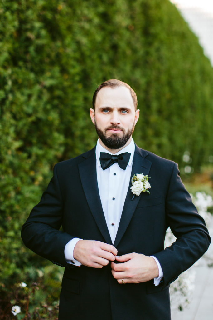 Groom buttoning his tux jacket