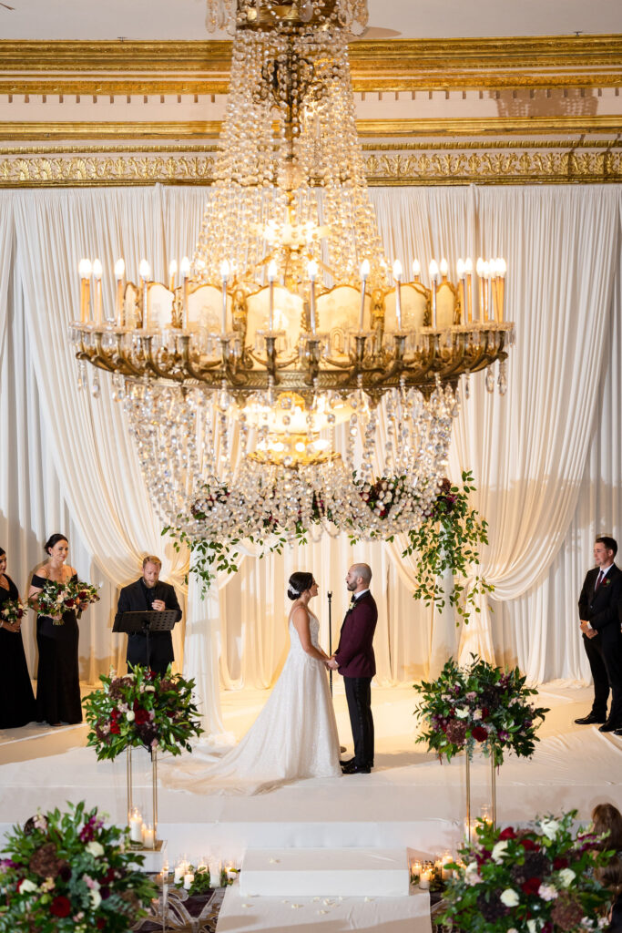 Luxury wedding ceremony draped with white linen and chandeliers