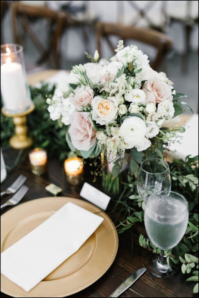 Gold, white, and cream wedding centerpiece and table setting with candlelight