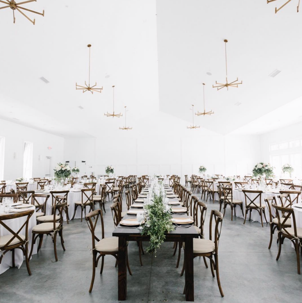 Wedding reception at The Hutton House with cross back chairs and greenery on a white backdrop