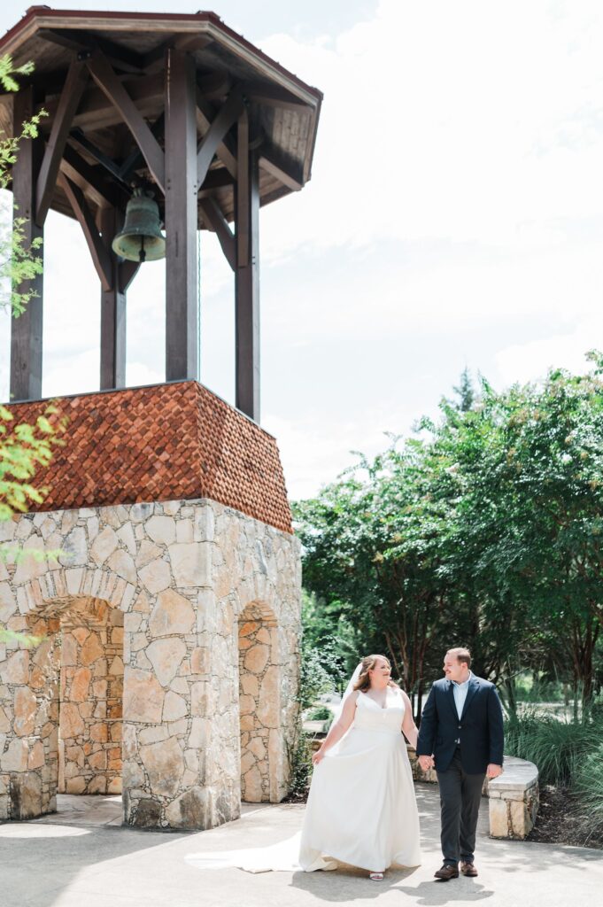 Bride and groom next to clock tower at Sacred Oaks wedding venue in Dripping Springs.