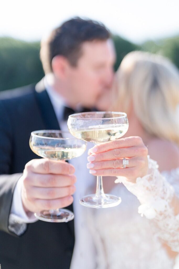 Newlyweds kissing and toasting champagne coupes