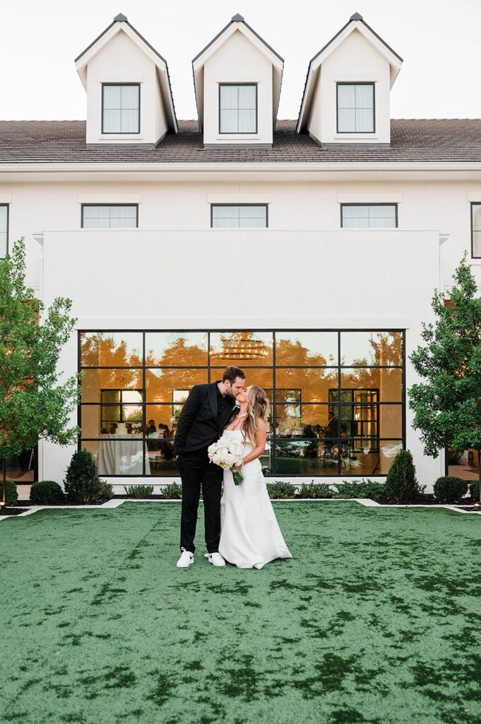 Newlyweds kissing outside wedding venue in Dripping Springs.