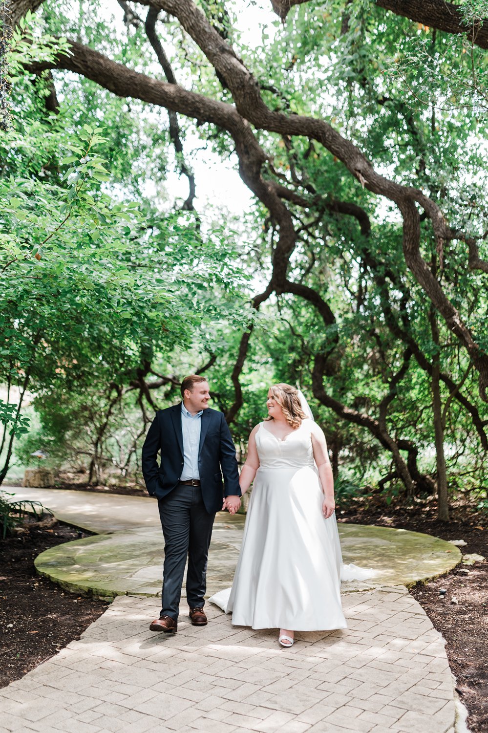 Newlyweds walking under a canopy of cedar trees